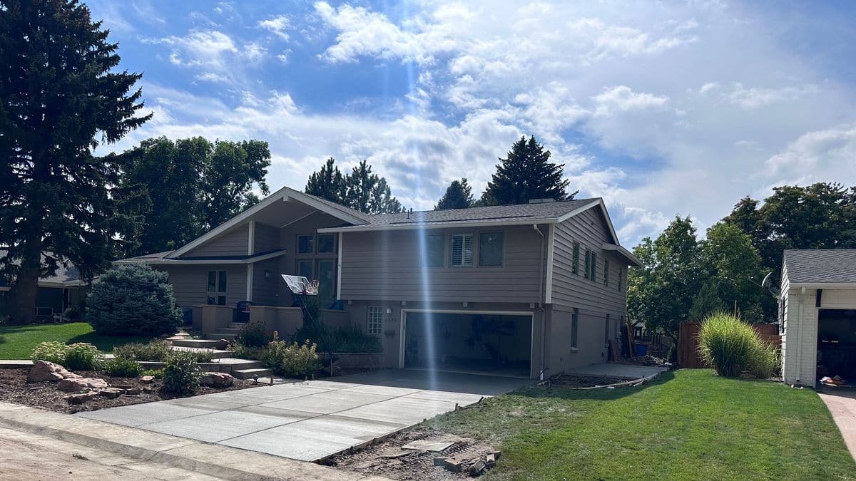 A finished concrete driveway in front of a two-storey home, seen from the street.